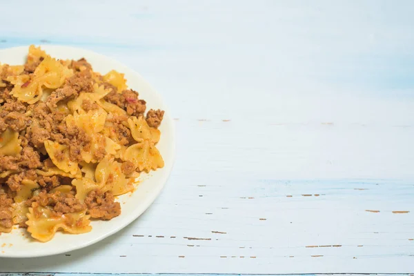 fresh Italian pasta with meat and spices on a light wooden background. a fork on a plate . the view from the top. space for text.