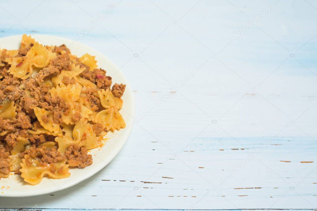 fresh Italian pasta with meat and spices on a light wooden background. a fork on a plate . the view from the top. space for text.