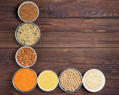 tanecikler kırmızı mercimek, basmati pilavı, karabuğday, nohut, tabakta darı. organik sağlıklı tahıllar. Tahta bir arka planda. Doğal vejetaryen sebze proteini. Yukarıdan manzara. Kapat.