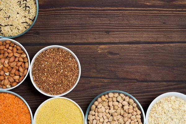 grains red lentils, basmati rice, buckwheat, chickpeas, millet in plates. organic healthy cereals. on a wooden background. natural vegetarian vegetable protein . the view from the top. space for text