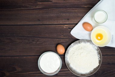 Maslenitsa Şubat ayında geleneksel bir bayramdır. Krep pişirmek için gerekli malzemeler. Yumurta, un, yumurta çırpıcı, koyu ahşap arka plan manzaralı. Üst görünüm, metin kopyalanacak yer, tarif.