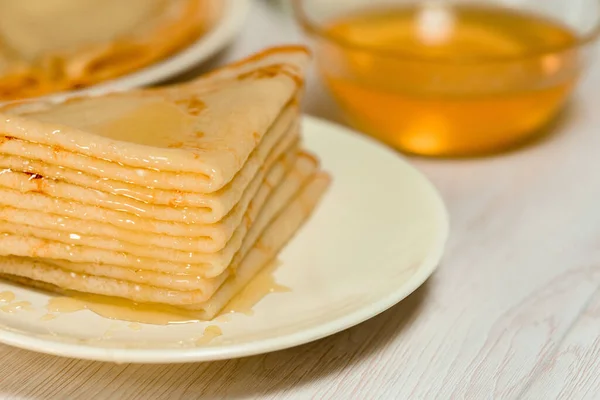 Maslenitsa es un día festivo a finales de febrero. tortitas con miel y leche sobre un fondo claro. la miel gotea por una pila de panqueques. De cerca. Blini. espacio para texto — Foto de Stock
