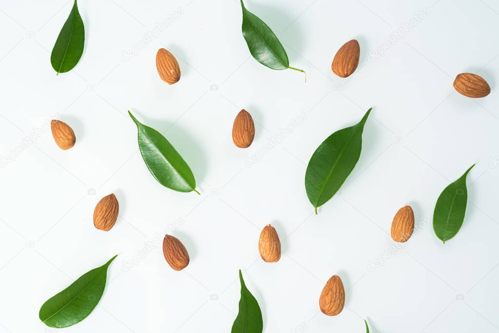 almonds and green leaves isolated on a white background. spring composition, top view. nutritious nut, healthy nutrition. flat lay