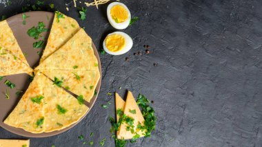Peynirli gözleme, şifalı ot ve Shrovetide için yumurta. Peynirli tortilla parçalara ayrılır ve üzerine peynir serpiştirilir. Karanlık bir arka planda, en üstteki manzarada. Metin için boşluk.