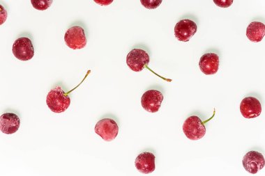 Fotoğraf boyunca beyaz arka planda bir grup donmuş kiraz. Yukarıdan manzara. Desen. Kapat. Meyvelerde buz kristalleri
