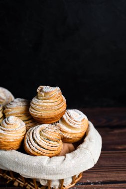 Modern moda hamur işleri, poğaça keki, kruvasan ve kek karışımı. Koyu ahşap bir masada, üzerine pudra şekeri serpiştirilmiş. Kopyalanacak yer, yukarıdan görünüm.