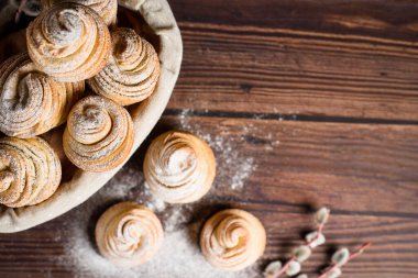 Lezzetli modern çörekler poğaça şeklinde kruvasanlardan yapılır. Tahta kaplamalı tahtadan bir sepetin üzerine pudra şekeri ve ahududu serpiştirilmiş kabuklular. Boşluğu kopyala.
