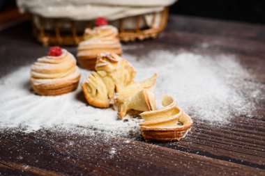 Modern çörekler pofuduk kruvasanlardan yapılır. Çörek şeklinde. Pudra şekerli koyu bir arka planda. Uzayı kopyala Yukarıdan manzara. Kapat..