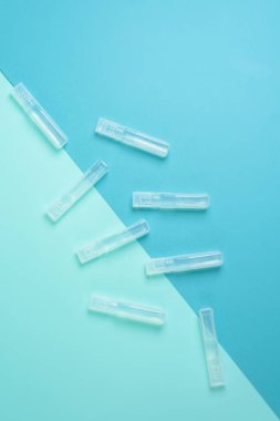 Mavi arka plandaki koronavirüs virüsünden şeffaf bir şişede sıvı aşı. Yukarıdan manzara. Bir salgında enfeksiyon tedavisi.