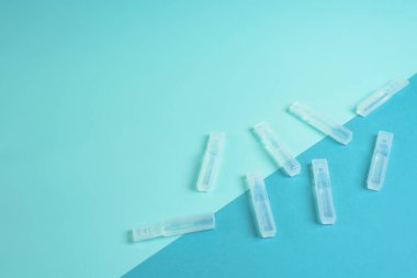 Mavi arka planda şeffaf bir koronavirüs şişesinde sıvı aşı. Yukarıdan manzara. Bir salgında enfeksiyon tedavisi.