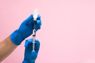 Pembe arka planda tıbbi mavi koronavirüs eldiveni olan bir virüs aşısı. Metin için boşluk. Salgının klinik terapisi. İnsanların sağlığıyla ilgilenmek..