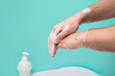 Koronavirüs enfeksiyonu sırasında ellerinizi dezenfektan sabunla yıkayın. Sabun köpüklü bir elin yakın çekimi. Ellerin antibakteriyel tedavisi. mavi arkaplanda.