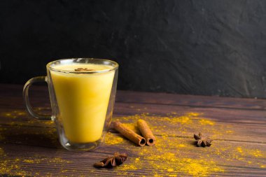 Zerdeçal tozlu altın sütlü latte ve koyu arkaplanda berrak bir bardakta malzemeler. Geleneksel Hint içeceği zerdeçal sütüdür. Yukarıdan görünüm, metin için boşluk.
