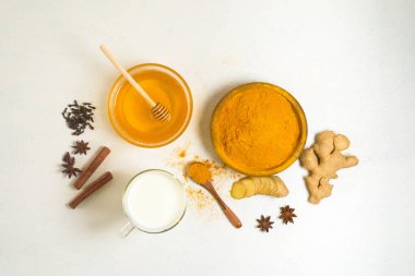 Hint geleneksel altın sütü, zerdeçal, zencefil, baharat, bal. İçkinin iyileştirici etkisi. Hafif bir arka planda altın bir içecek için malzemeler. Antiviral antioksidan. Yukarıdan görünüm.