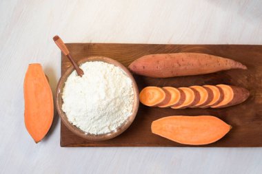 Tahta tabakta tatlı patates unu. Tatlı patatesler hafif arka planda sağlıklı beslenmek için kullanılan organik bir vejetaryendir.