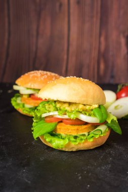 Mercimek dilimli vejetaryen burger. Sebze proteinli vejetaryen yiyecekler, otlar, domatesler, ahşap arka planda soğanlar. Yukarıdan görünüm.