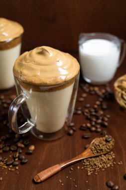 Koyu ahşap arka planda, berrak bardaklarda soğuk dalgon kahvesi. Şekerden köpük ve hazır kahve soğuk sütle karıştırılır. Hint usulü kremalı kahve. kahve çekirdekleri.