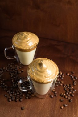 Koyu ahşap arka planda, berrak bardaklarda soğuk dalgon kahvesi. Şekerden köpük ve hazır kahve soğuk sütle karıştırılır. Kore ve Hindistan kremalı kahvesi..