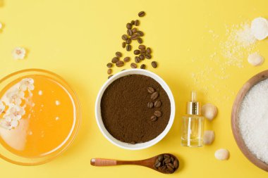 Doğal organik malzemeler, deniz tuzu, kahve fırçası, bal ve sarı arka planda sert bir vücut fırçası. Selülitler için ev cilt bakımı. Cilt bakımı konsepti, spa. Yukarıdan görünüm.