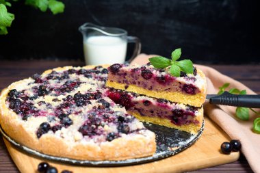 Frenk üzümlü turta, kurabiye, taze böğürtlen. Turta parçalara ayrılmış ve tepesine pudra şekeri serpilmiş. Turta reyonundaki bir parçanın yakın çekimi..