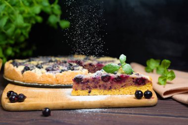 Frenk üzümlü turta, kurabiye, taze böğürtlen. Üzerine pudra şekeri serpiştirilmiş parça parça pasta üst görünümü.