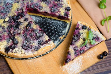 Frenk üzümlü turta, kurabiye, taze böğürtlen. Üzerine pudra şekeri serpiştirilmiş parça parça pasta üst görünümü.