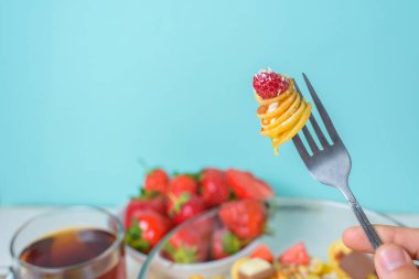 Çilekli, muzlu, çikolatalı, hindistan cevizli ve ballı küçük krepler mavi arka planda bir tabakta. Gıda eğilimi 2020.