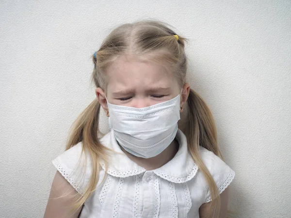 Little girl in a medical mask. Child with a sad face, closed eyes