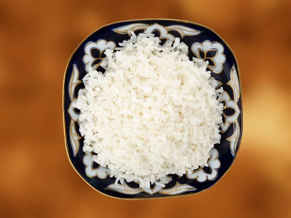 Beautiful dish with boiled rice on a gold background. View from above