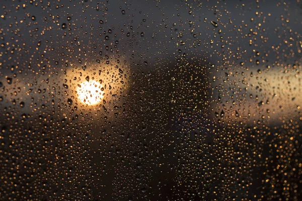 雨落在窗口与城市的模糊的背景 — 图库照片