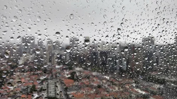 都市のぼやけた背景のウィンドウに雨粒します — ストック写真