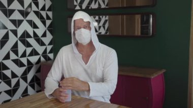 Alkol jeli sürüyorum. Koruyucu maskeli, evde dezenfektanla el temizleyen olgun bir adam. Virüs koruması. Salgın. Coronavirus. Covid 19.  