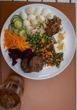 Sağlıklı yemek. Bıldırcın yumurtası, salatalık, havuç, bezelye, fasulye filizi, pancar, sığır burger, tofu ve tohum.. 