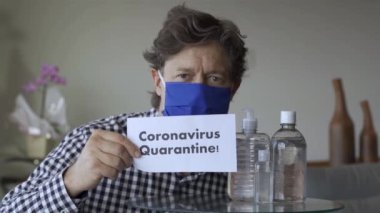 Slogan: Karantina. Olgun bir adam elinde karantina tabelasıyla kameranın önünde duruyor.. 