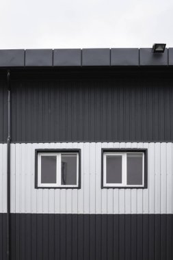 Pencereli bir binanın duvarında siyah-beyaz yuvarlak metal kaplama dokusu. Çelik arka planı galvanize et.