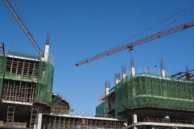 Mavi gökyüzüne karşı vinç ve inşaat alanı. İnşaatın bitmemiş binasının metal inşaatı. Crane kulesi çok katlı depo inşaatı için kullanılıyor.