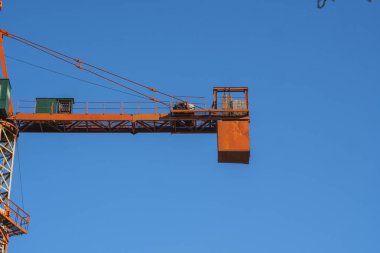 Çok katlı depolama ya da başka bir yapı için inşaat alanında mavi gökyüzüne karşı kule vinci.