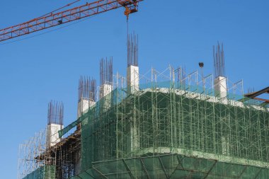 Mavi gökyüzüne karşı vinç ve inşaat alanı. İnşaatın bitmemiş binasının metal inşaatı. Crane kulesi çok katlı depo inşaatı için kullanılıyor.