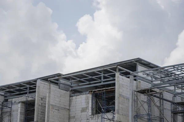 Building and Construction Site in progress. Building construction site against cloudy sky. Metal construction of unfinished building on construction of multi storage building.