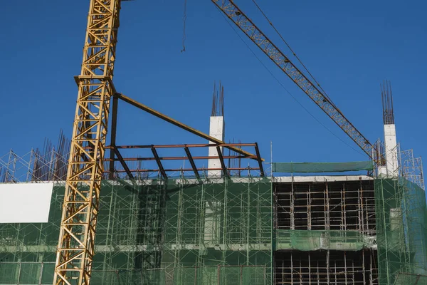 Mavi gökyüzüne karşı vinç ve inşaat alanı. İnşaatın bitmemiş binasının metal inşaatı. Crane kulesi çok katlı depo inşaatı için kullanılıyor. — Stok fotoğraf