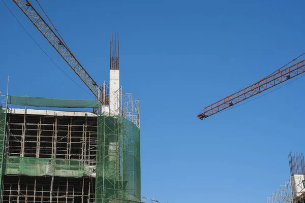 Mavi gökyüzüne karşı vinç ve inşaat alanı. İnşaatın bitmemiş binasının metal inşaatı. Crane kulesi çok katlı depo inşaatı için kullanılıyor. — Stok fotoğraf