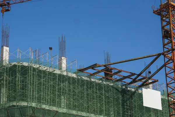 Kran und Baustelle vor blauem Himmel. Metallkonstruktion des Rohbaus auf dem Bau. Turmdrehkran-Einsatz für den Bau eines Mehrzweckgebäudes. — Stockfoto