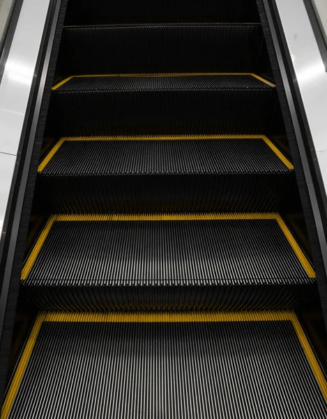 Moderno sistema electrónico de escaleras mecánicas en movimiento. Las escaleras mecánicas se están moviendo hacia arriba.El suelo es una línea recta. Negro con banda amarilla . — Foto de Stock