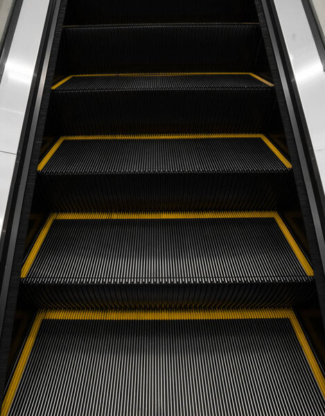 Modern escalator electronic system moving. Escalator is moving up.The ground is a straight line. Black with yellow band.