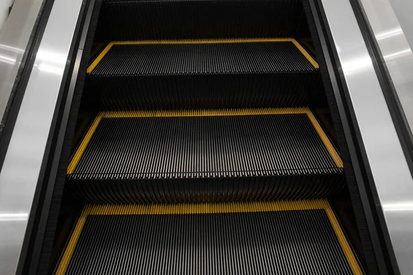 Modern escalator electronic system moving. Escalator is moving up.The ground is a straight line. Black with yellow band.