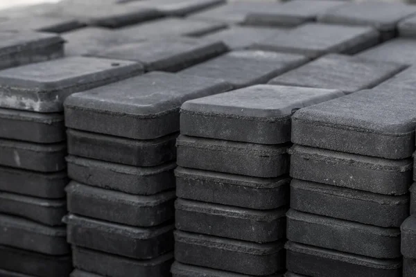 Stack of paving stone on construction site. Bricks for paving stones stacked in stacks, background texture structure. Gray pavement bricks for pavement road.