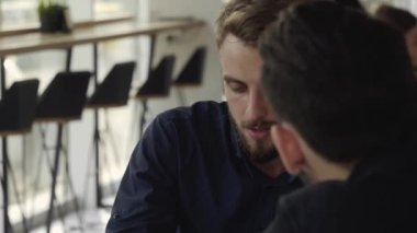 İki neşeli iş adamı bir şey tartışıyor ve kafede dizüstü bilgisayar ve telefonlarla otururken gülümsüyor. İki başarılı genç meslektaşımız, kafeteryadaki organizasyon anlarını teker teker tartışıyor..