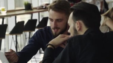 İki neşeli iş adamı bir şey tartışıyor ve kafede dizüstü bilgisayar ve telefonlarla otururken gülümsüyor. İki başarılı genç meslektaşımız, kafeteryadaki organizasyon anlarını teker teker tartışıyor..