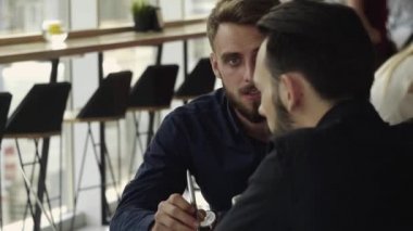 İki neşeli iş adamı bir şey tartışıyor ve kafede dizüstü bilgisayar ve telefonlarla otururken gülümsüyor. İki başarılı genç meslektaşımız, kafeteryadaki organizasyon anlarını teker teker tartışıyor..