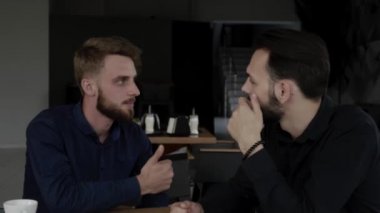 İki neşeli iş adamı bir şey tartışıyor ve kafede dizüstü bilgisayar ve telefonlarla otururken gülümsüyor. İki başarılı genç meslektaşımız, kafeteryadaki organizasyon anlarını teker teker tartışıyor..